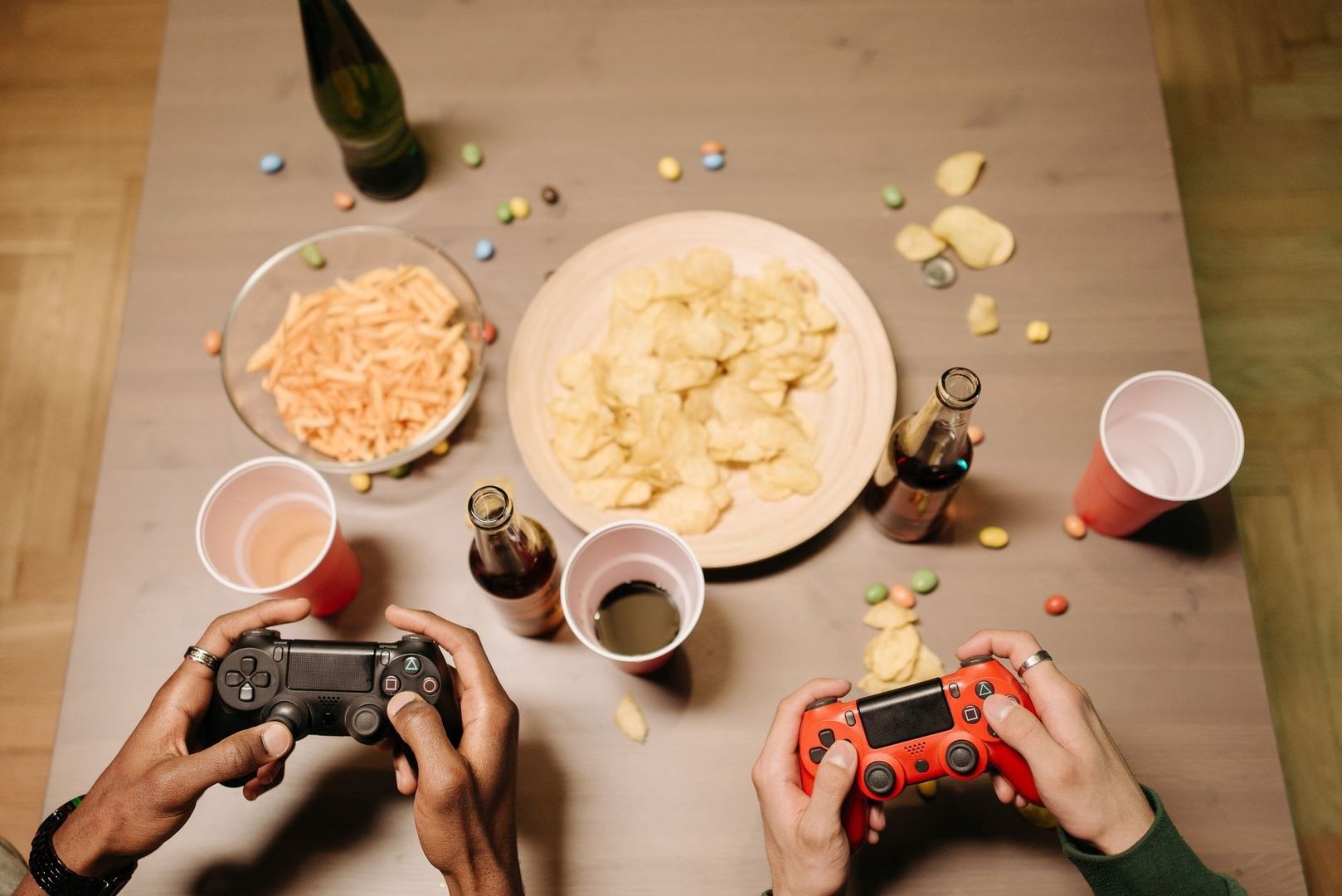 To personer spiller videospill ved et bord med snacks og drikke