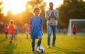 Ung fotballspiller går med ballen mens en voksen følger etter